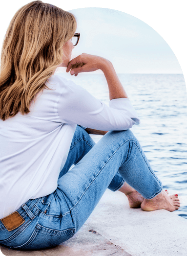 Picture of a woman sitting at the edge of a seawall.